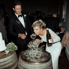 a man and woman standing next to each other in front of wine glasses