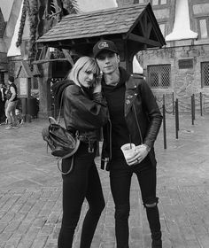 a man and woman standing next to each other in front of a building with a clock on it