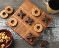 a wooden board game with crosses and nuts on it next to a cup of coffee