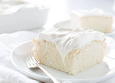 a piece of cake on a white plate with a fork and bowl in the background