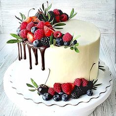 a white cake with berries, raspberries and chocolate drizzle on top