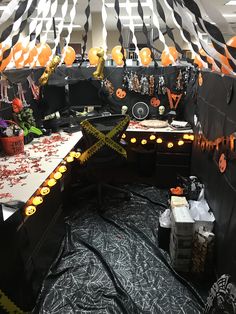 a room decorated for halloween with black and orange decorations on the walls, white tablecloths and balloons