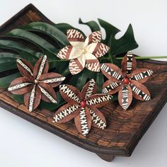 a wooden tray with flowers and leaves on it