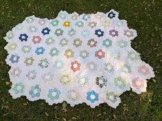 a quilt is laying on the grass with flowers all over it's sides and center