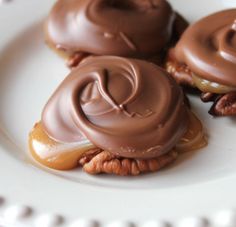 two chocolate covered donuts sitting on top of a white plate