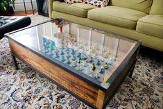 a living room with a couch, coffee table and glass display case on the floor