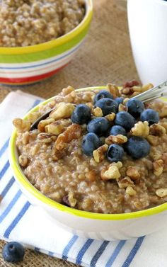 a bowl of oatmeal with blueberries and walnuts on the side