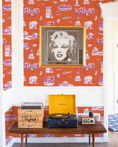 an old record player sitting on top of a wooden table in front of a painting