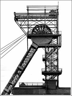 a black and white photo of a large metal structure with a clock on it's side