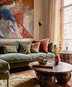 a living room filled with furniture and a large painting on the wall above it's windows