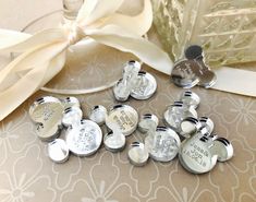 a bunch of silver buttons sitting on top of a table next to a white ribbon