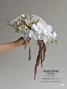 a hand holding a paper fan with flowers on it and the words good time written in chinese