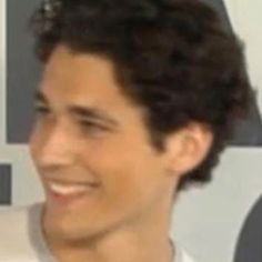 a young man smiling and wearing a tie