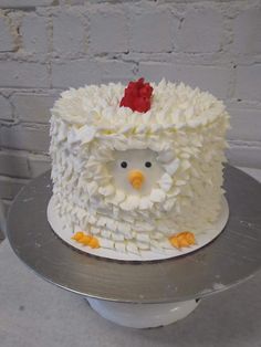 a cake decorated with white frosting and a red flower on top is sitting on a silver platter