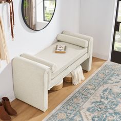 a white bench sitting on top of a hard wood floor next to a mirror and rug