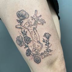 a woman's thigh with a rabbit and flowers tattoo on her left side calf