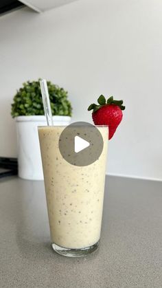 a smoothie in a glass with a straw and a strawberry on the top, sitting on a table