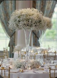 an elegant centerpiece with baby's breath flowers is displayed on a round table