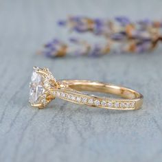 a close up of a diamond ring on top of a table with lavender flowers in the background