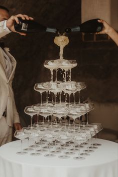 two people pouring champagne into wine glasses on top of a table