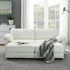 a white couch sitting in front of a window with a blanket on top of it