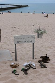 shoes are lined up in the sand near a sign that says welcome to our wedding