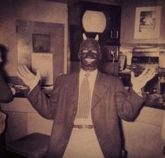 an old photo of a man wearing a mask and holding his hands up in the air