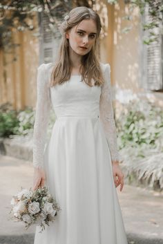 a woman in a white wedding dress holding a bouquet and wearing a long sleeved top