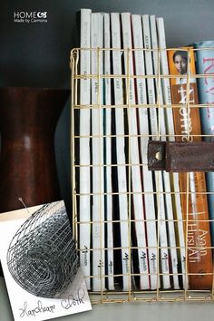 some books are sitting on a shelf next to a wire basket and a card holder