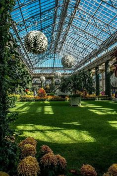 the inside of a large building with lots of plants and flowers in front of it