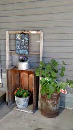 two potted plants sitting on top of a wooden stand next to a sign that says be in my garden