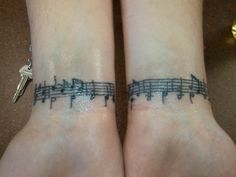 two wrist tattoos with musical notes on them