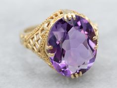 "This beautiful vintage filigree setting has an earthy feel, with curling textured motifs repeating in a tapering, lattice-style pattern. Set in the center is a stunning oval amethyst of the deepest shade of plum and lilac reflecting light to and from the golden filigree. Metal: 14K Yellow Gold Gem: Amethyst Gem Measurements: 13.6 x 11.0 mm, Oval Ring Size: 6.75 Marks: \"14K\" Stamped on the inside band To view a video of this piece check out the link below: https://vimeo.com/787965601 SKU #: A1 Yellow Gold Amethyst Ring, Amethyst Cocktail Ring, Sapphire Solitaire Ring, Petite Earrings, Gold Amethyst Ring, Reflecting Light, Sapphire Solitaire, Gold Cocktail Ring, Gold Signet Ring