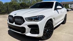 a white bmw suv parked in front of a fence