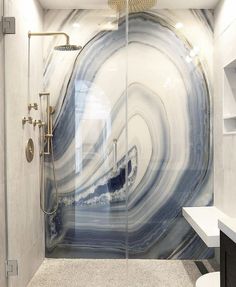 a bathroom with a glass shower door and marble wall