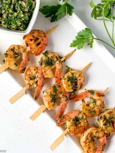 grilled shrimp skewers with pesto and parsley on a white platter