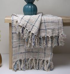 a blue vase with flowers in it sitting on a table next to a plaid blanket