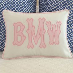 the monogrammed pillow has pink letters on it and is next to two blue pillows