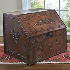 a large metal box sitting on top of a wooden table next to a window with pine cones