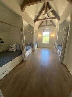 two beds in a room with wooden floors and white walls, along with wood flooring