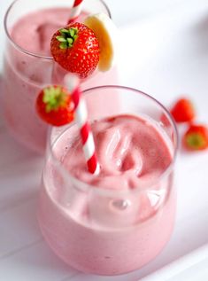 two glasses filled with pink smoothie and strawberries