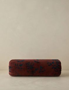 a red and blue pillow sitting on top of a white floor next to a wall