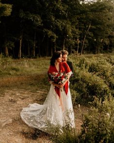 a bride and groom standing in the woods