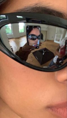 a person wearing sunglasses is taking a selfie with their cell phone in the mirror