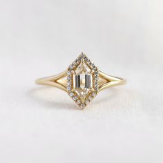 a yellow gold engagement ring with an emerald cut diamond surrounded by small round brilliant diamonds