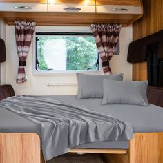 a bed in a room with a window and curtains on the windowsills behind it