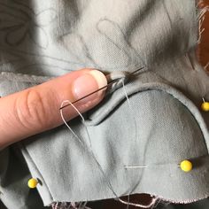 someone is stitching together some thread and yellow beads on the fabric with their thumbnails