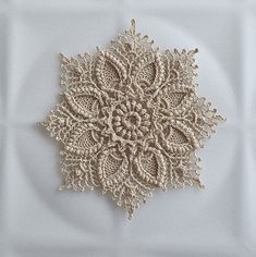 a crocheted doily is shown on a white surface with an intricate design