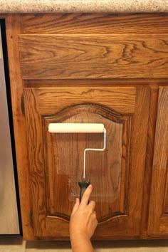 a person using a paint roller to paint cabinet doors with text overlay that reads the hottest new way to paint cabinets