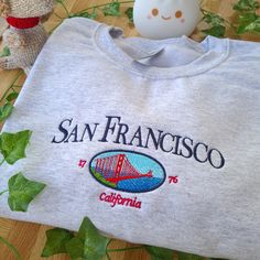 San Francisco Embroider Sweatshirt, California Sweatshirt, San Francisco City Crewneck, Vintage Sweatshirt, Vintage Crewneck, USA States Jumper, Vintage New York Crewneck, Perfect Cosy Jumper for her, Vintage Crewneck Location, Location City Sweatshirt, Vintage City Embroidered Sweater I've included images showing the design on a Ash Sweatshirt, please message me for specific sweatshirt colour requests/a request for changing the embroidery colour. Check out our Shop filled with so many Designs! Vintage College Sweatshirt With Embroidered Text, Vintage Long Sleeve T-shirt With Embroidered Graphics, Vintage Embroidered Crew Neck T-shirt, Vintage Embroidered Sweatshirt, Crew Neck Sweatshirt Aesthetic, California Sweater, City Sweatshirt, California Sweatshirt, Vintage City